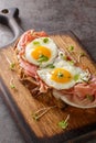 Strammer Max German Sandwich with Cured Ham and Eggs closeup on the wooden board. Vertical