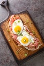 Strammer Max German Sandwich with Cured Ham and Eggs closeup on the wooden board. Vertical top view