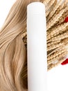 A strand of blond hair with a bottle of shampoo on a white background. Close-up. Royalty Free Stock Photo