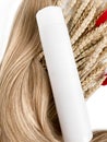 A strand of blond hair with a bottle of shampoo on a white background. Close-up. Royalty Free Stock Photo