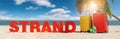 Strand German for: Beacj concept with slogan on the beach with Suitcase, Palm tree, flip-flops and blue sky