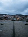 Stranded beached fishing boat vessle ship on coastline shore of seaside town village Combarro Galicia Spain at low tide