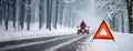 Stranded car with warning triangle on snowy road and person waiting. A vehicle breakdown in winter conditions with a Royalty Free Stock Photo