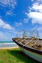 Stranded fisherman boat on green grass toward sea view at sunny day and cloudy blue sky