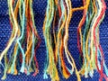 Strands of colorful threads against a blue hue