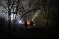 strange light in a dark forest at night. Silhouette of person standing in the dark forest with light. Dark night in forest at fog