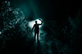 strange light in a dark forest at night. Silhouette of person standing in the dark forest with light. Horror halloween concept. Royalty Free Stock Photo