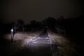 strange light in a dark forest at night. Silhouette of person standing in the dark forest with light. Dark night in forest at fog