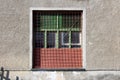 Strange looking colorful old abandoned factory building window with wooden frame and strong metal protection net