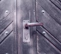 A strange old wooden entrance door with a rusted door handle. A vintage door knob. Closeup of a traditional door with a Royalty Free Stock Photo