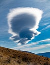 Strange shaped clouds in blue sky with sunlight above Dinaric Alps. Cloudy blue sky with white cloud in form of lenses lenticular