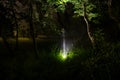 Strange silhouette in a dark spooky forest at night, mystical landscape surreal lights with creepy man