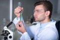 Young handsome explorer keeping and overlooking test tube. Royalty Free Stock Photo