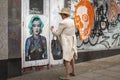 Strangely dressed lady standing in front of Marilyn graffiti