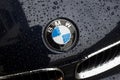 Closeup of rain drops of BMW logo on black car front parked in the street Royalty Free Stock Photo