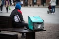 Delivery man sitting on wooden bench in the street, deliveroo is a british delivery company