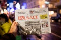 Man holding L`Alsace French newspaper at press kiosk announcing the death of