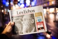 Man holding Les Echos newspaper at French press kiosk announcing the death of