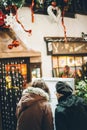 Rear view of two women looking at the restaurant menu on the street with Christmas decoration on the facade of the