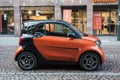 Profile view of orange and black smart car parked in the street Royalty Free Stock Photo
