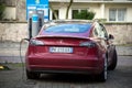 Rear view of red testa car charging in the street, tesla is the famous american brand of electric cars