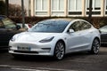 front view of white testa car parked in the street, tesla is the famous american brand of electric cars