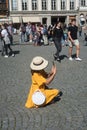 Portrait of tourist photographer wearing an orange dress and summer hat shooting photo with her smartphone in the street