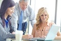 Strategizing together. Three businesspeople working together at a conference table with a laptop. Royalty Free Stock Photo