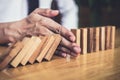 Strategy and successful intervention concept for business, businessman hand Stopping Falling wooden Dominoes effect from Royalty Free Stock Photo