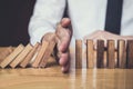 Strategy and successful intervention concept for business, businessman hand Stopping Falling wooden Dominoes effect from Royalty Free Stock Photo