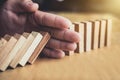 Strategy and successful intervention concept for business, businessman hand Stopping Falling wooden Dominoes effect from Royalty Free Stock Photo