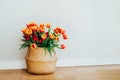 Straw bag basket with a bunch of fresh red and yellow tulips on the floor with white wall background. Gift Royalty Free Stock Photo