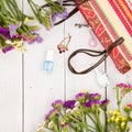 straw bag, colorful flowers, cosmetics makeup, bijou and essentials on white wooden background Royalty Free Stock Photo