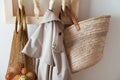 straw bag, mesh bag and trench on handmade wooden hang. Concept of slowlife home