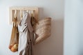 straw bag, mesh bag and trench on handmade wooden hang. Concept of slowlife home