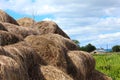 Straw bales and blue bright sky with clouds. Stock of hay for the winter in the village. Haystacks against the background of the Royalty Free Stock Photo