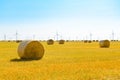 Straw Bales on the Bright Yellow Field under Blue Sky. Wind Generator Turbines on the Background Royalty Free Stock Photo