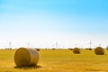 Straw Bales on the Bright Yellow Field under Blue Sky. Wind Generator Turbines on the Background Royalty Free Stock Photo