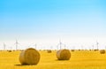 Straw Bales on the Bright Yellow Field under Blue Sky. Wind Generator Turbines on the Background Royalty Free Stock Photo