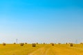 Straw Bales on the Bright Yellow Field under Blue Sky. Wind Generator Turbines on the Background Royalty Free Stock Photo