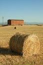 Straw bales during collection in the summer and with a warehouse in the background Royalty Free Stock Photo