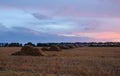 Straw bales on farmland field with pink sunset sky Royalty Free Stock Photo