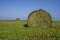 Straw bales on a field in the foreground. Harvest of hay. Clouds in the sky. Agricultural farm. Hills with cultivated fields and