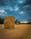 Straw bales stacked in a field under a threatening sky. Royalty Free Stock Photo