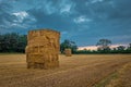 Straw bales stacked in a field under a threatening sky. Royalty Free Stock Photo