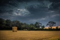 Straw bales stacked in a field under a threatening sky. Royalty Free Stock Photo