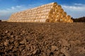 straw bales stacked in a pyramid shaped pile on arable land Royalty Free Stock Photo