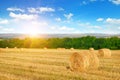 Straw bales on wheat field and sunrise on blue sky Royalty Free Stock Photo