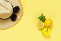 Straw beach foman`s hat and black sun glasses with citrics water on yellow. Top view. Flat lay. Royalty Free Stock Photo