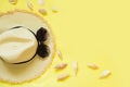 Straw beach foman`s hat and black sun glasses with seashells on yellow background. Top view. Flat lay.